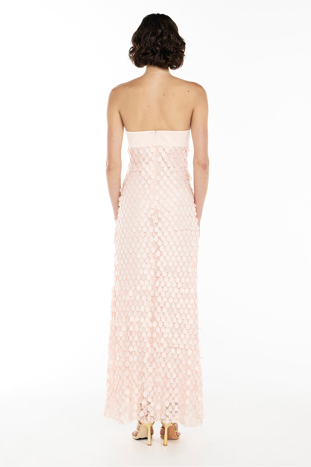 Back view of Woman wearing pink strapless textured dress with petal detail
