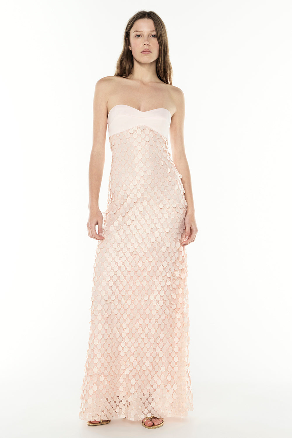 Woman wearing a strapless, long, patterned pink dress on a white background