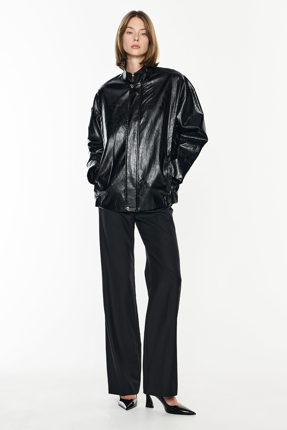 Person wearing a shiny black jacket and pants on a white background